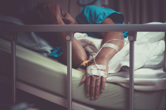 Kobieta w szpitalny łóżku, z wenflonem w dłoni