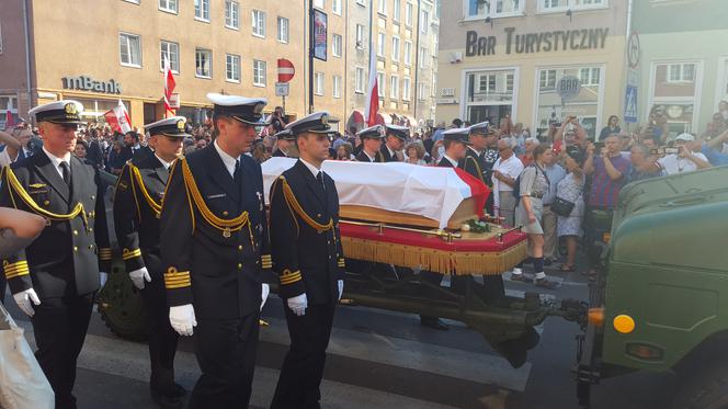 Kondukt ruszył. Trumny bohaterów są wiezione przez dwa pojazdy wojskowe.