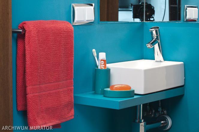 Kolor ścian w odcieniu ciepłego niebieskiego w łazience z dodatkami koloru czerwonego