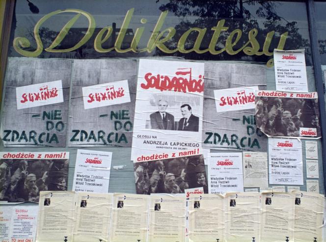 Plakaty wyborcze Andrzeja Łapickiego, startującego z listy Solidarności, w witrynie sklepu, Warszawa, czerwiec 1989.