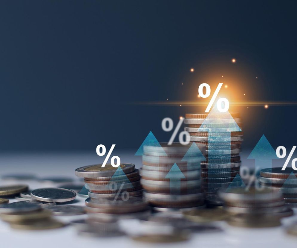 Stosy monet z symbolami procentowymi i strzałkami wzrostu, ilustrujące dynamikę finansową, rynek walutowy oraz notowania giełdowe. Temat opisany na Super Biznes, gdzie dowiesz się więcej o wynikach XTB i zmienności na giełdzie.