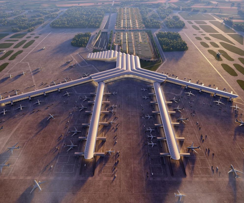 Wizualizacja Portu Polska z lotu ptaka, ukazująca rozległy terminal w kształcie litery Y z licznymi rękawami pasażerskimi i samolotami na płycie postojowej. W tle widoczny obszar z przygotowywaną infrastrukturą, w tym planowane bocznice kolejowe dla Portu Polska. Więcej o tej inwestycji na Architektura Murator Plus.