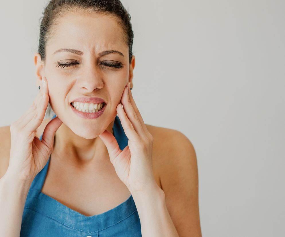 Młoda kobieta dotyka szczęki.