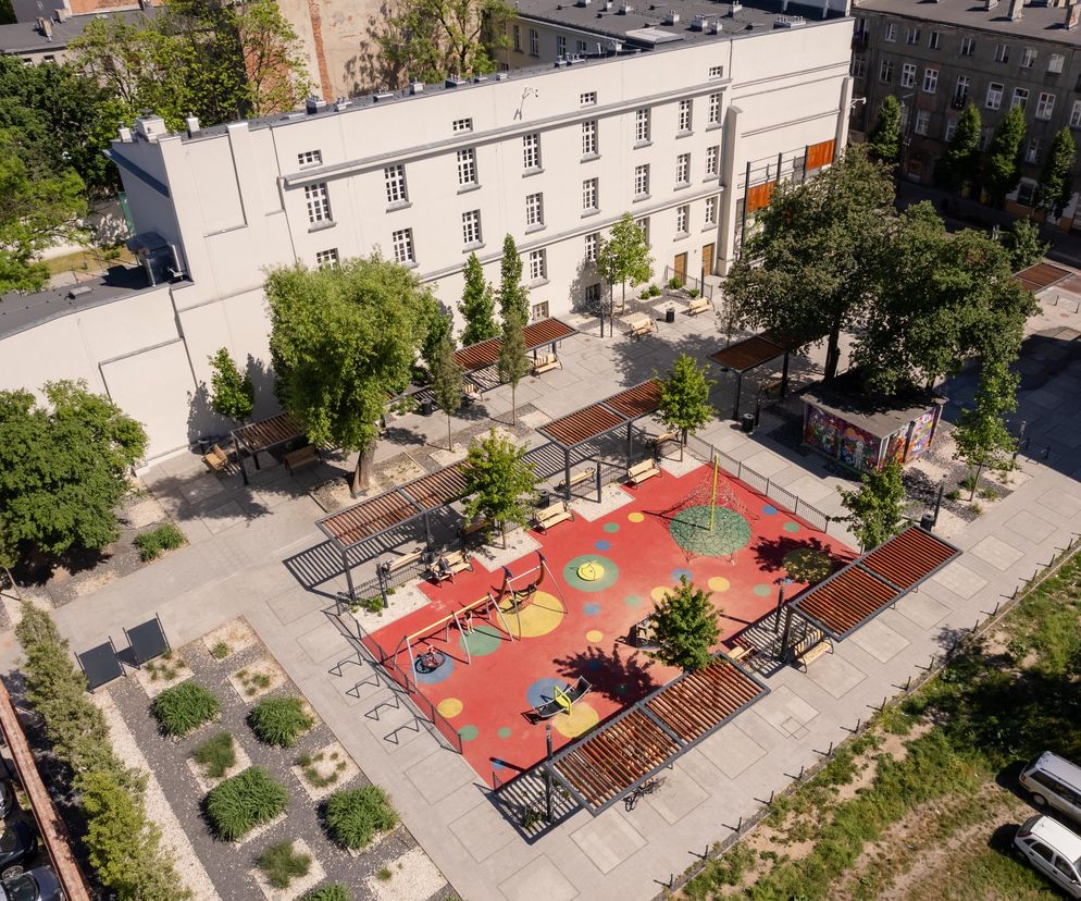 Widok z góry na zrewitalizowany Pasaż Hilarego Majewskiego w Łodzi, autorstwa Jakuba Krzysztofika. Widoczny plac zabaw z czerwonym podłożem i kolorowymi okręgami, altany z drewnianymi pergolami oraz zieleń. Przy pasażu znajdują się odnowione budynki, a więcej o tego typu architekturze przeczytasz na Architektura Murator Plus.