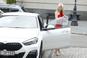 Magdalena Ogórek w BMW za ćwierć miliona. Czerwona sukienka i czarna felga