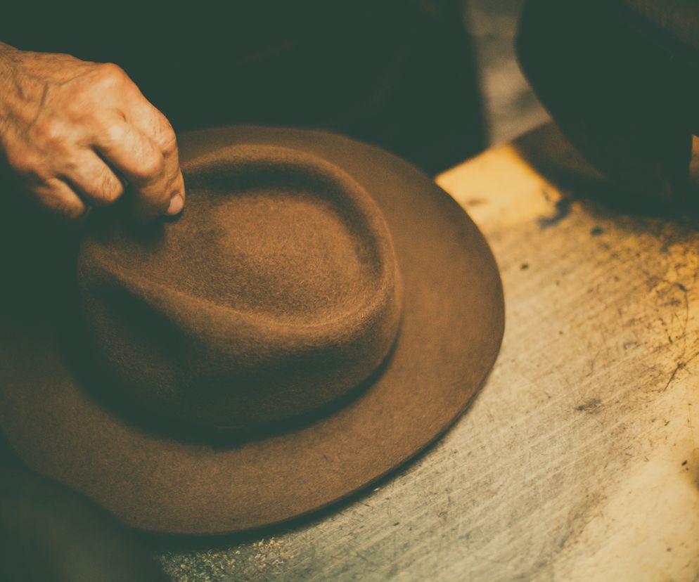 Mężczna trzyma w dłoniach kapelusz