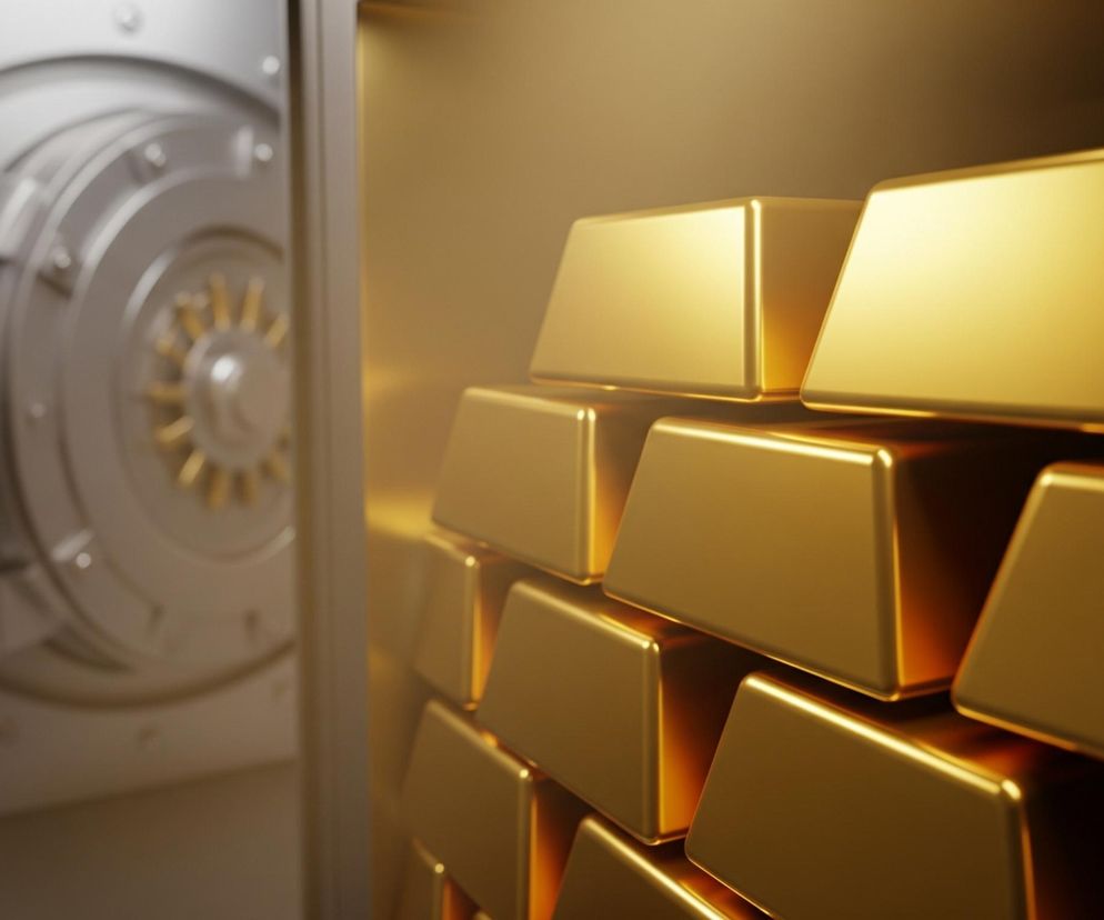 Prawa strona obrazu wypełniona jest piramidą złotych sztabek, ciasno ułożonych jedna na drugiej, które intensywnie odbijają światło, tworząc refleksy i gradienty od jasnego złota do ciemniejszego brązu w cieniu. W lewej części obrazu, na drugim planie i poza ostrością, widoczna jest uchylona, masywna, metalowa, srebrzysta tarcza skarbca, z centralnie umieszczonym złotym mechanizmem i okrągłymi nitami rozmieszczonymi wokół jej obwodu. Cała scena utrzymana jest w ciepłych barwach, ze dominującymi odcieniami złota i brązu, kontrastującymi z chłodniejszym srebrem tarczy.