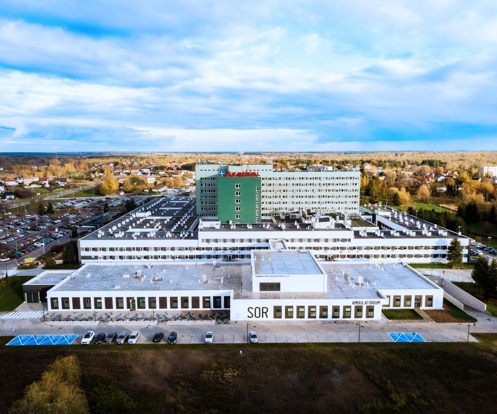 Nowy budynek Szpitalnego Oddziału Ratunkowego Mazowieckiego Szpitala Specjalistycznego w Radomiu z lotu ptaka. Jasna bryła z napisem SOR i Ambulatorium, otoczona parkingiem, wyróżnia się na tle zielonego otoczenia. Projekt autorstwa Szymona Mazurka można poznać na Architektura Murator Plus.