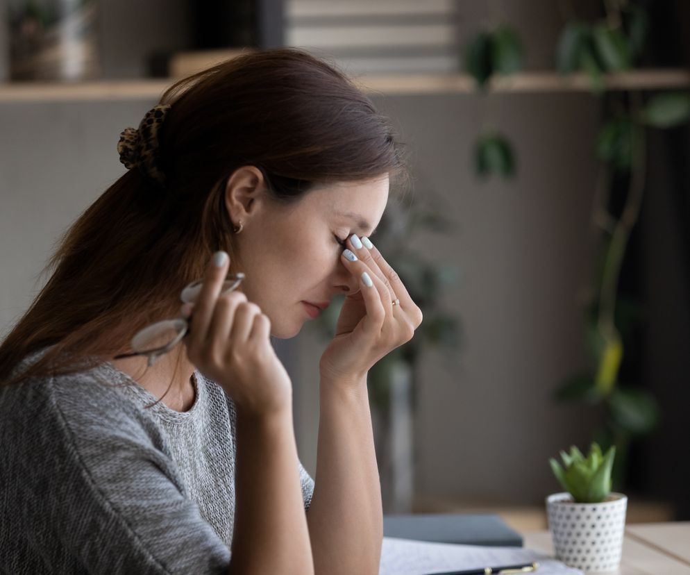 Kobieta z bólem głowy w trakcie pracy przy laptopie