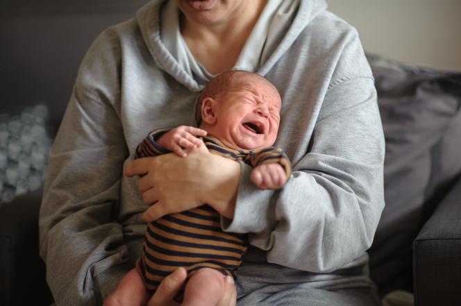Płaczący noworodek w ramionach taty