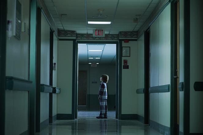 chłopiec w piżamie na pustym szpitalnym korytarzu