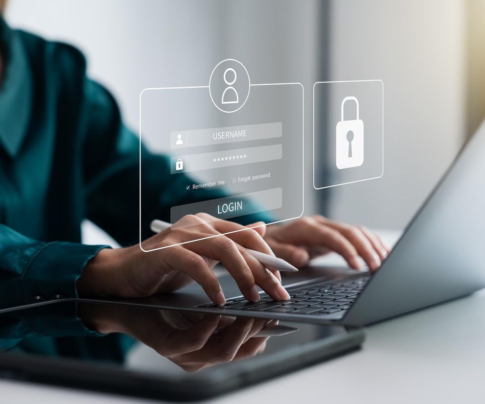 Osoba logująca się do systemu na laptopie, obok ekran z polem na nazwę użytkownika i hasło, symbolizujący cyberbezpieczeństwo. O szkoleniach z tego zakresu dla dziennikarzy przeczytasz na Super Biznes.