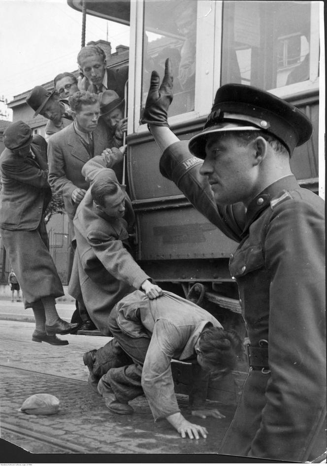 Kraków. Pasażer wypadł z przepełnionego tramwaju. Widoczni ludzie podróżujący na stopniach. Fotomontaż, 1941