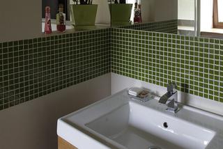 Zielona łazienka z mozaiką nad umywalką