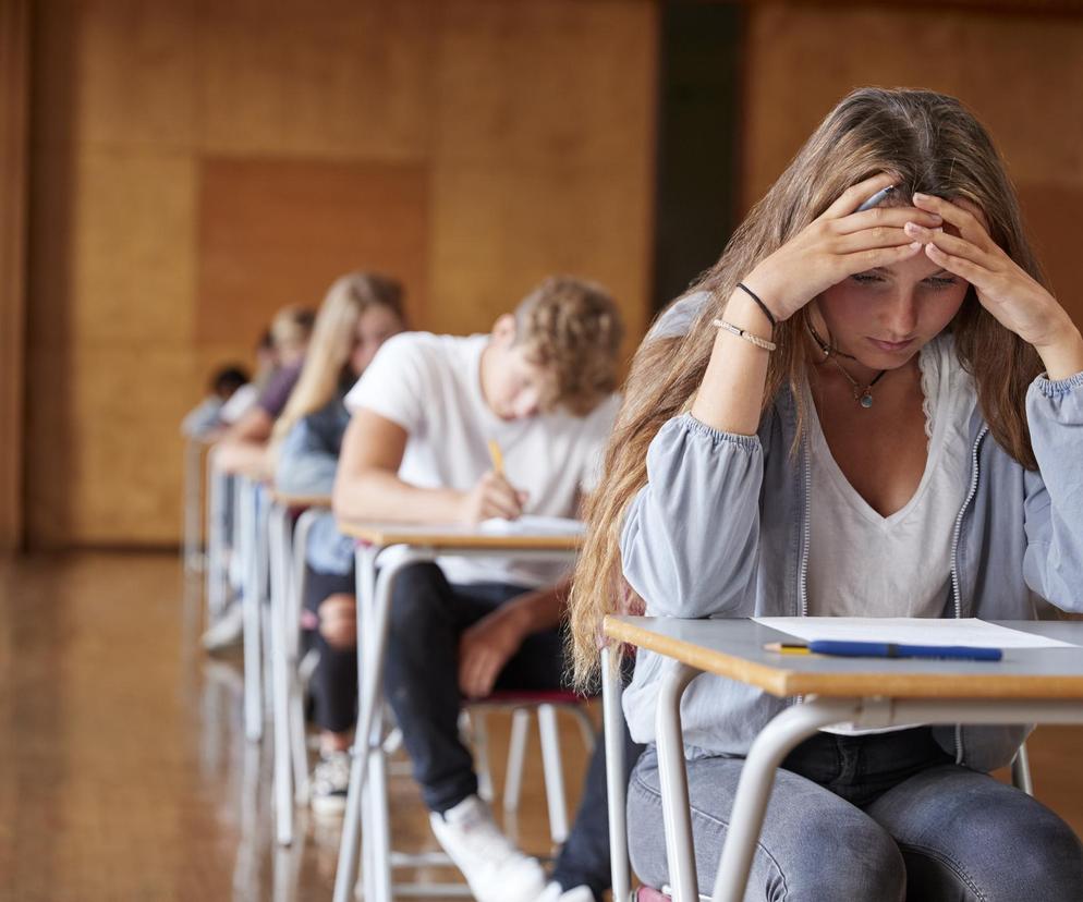 uczniowie przy stolikach w czasie zdawania testu