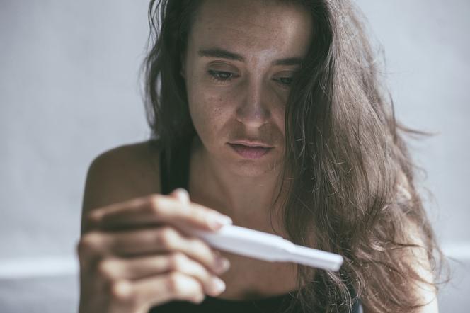 Smutna kobieta sprawdza test ciążowy