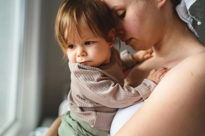 Smutna mama z dzieckiem na rękach