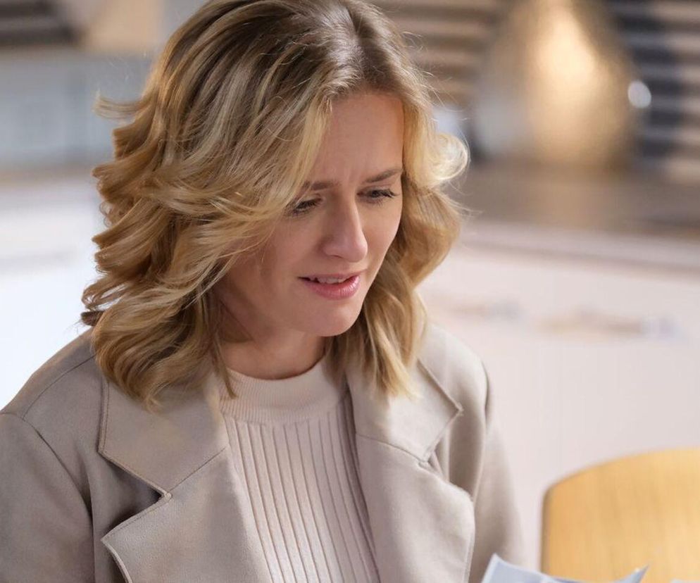 Julia (Marta Chodorowska) z serialu M jak miłość ze zmartwioną miną, w beżowym swetrze i płaszczu. Blond włosy swobodnie opadają na ramiona. Scena nawiązuje do zaskakującej ciąży bohaterki, o której można przeczytać więcej na Super Seriale.