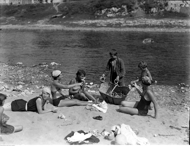 Plażowicze podczas wypoczynku. Widoczny chłopiec sprzedający bajgle. Zdjęcie zrobione w 1929 roku 