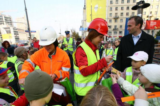 Pracownicy firmy Skanska rozdają uczniom opaski odblaskowe 