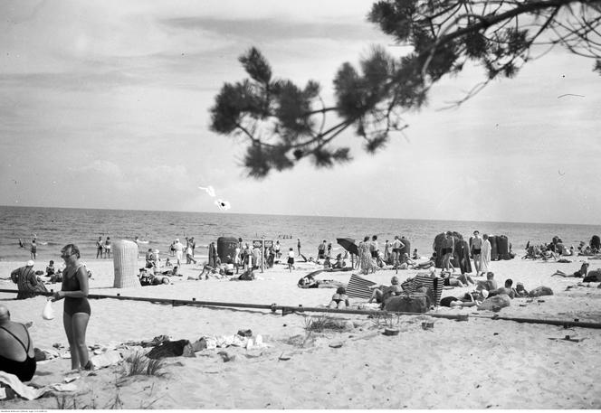 Plażowicze podczas wypoczynku nad morzem Bałtyckim. W tle port. Zdjęcie zrobiono w Gdyni pomiędzy 1923-1935 rokiem