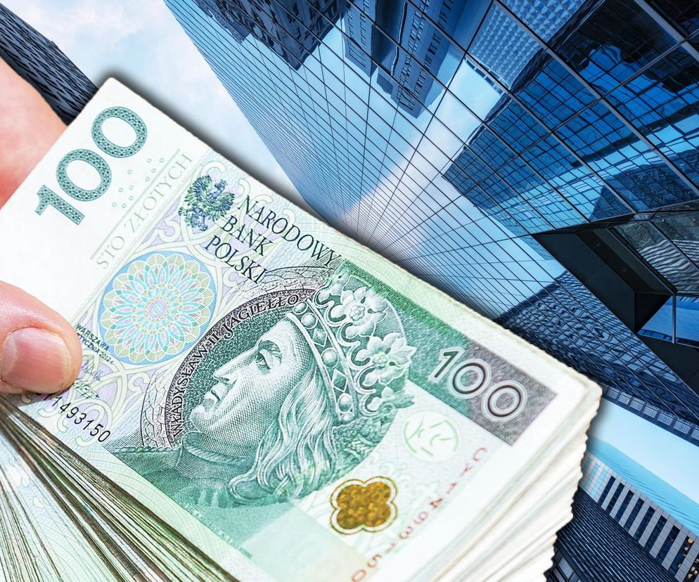 Stos banknotów 100-złotowych, trzymanych w ręce, na tle nowoczesnych biurowców o szklanych elewacjach. To ilustracja do tematu podatku od nieruchomości, o którym przeczytasz więcej na Super Biznes.