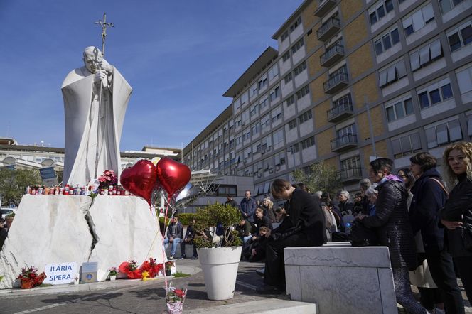 Świeczki, kartki z życzeniami, balony w kształcie serca, kwiaty składane są pod pomnikiem Jana Pawła II przed rzymską Polikliniką Gemelli