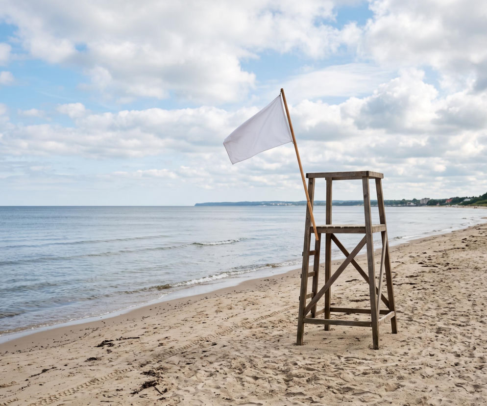 Biała flaga na wieży ratowniczej przy pustej plaży. O bezpiecznych kąpielach w Ustroniu Morskim przeczytasz na SE Szczecin.