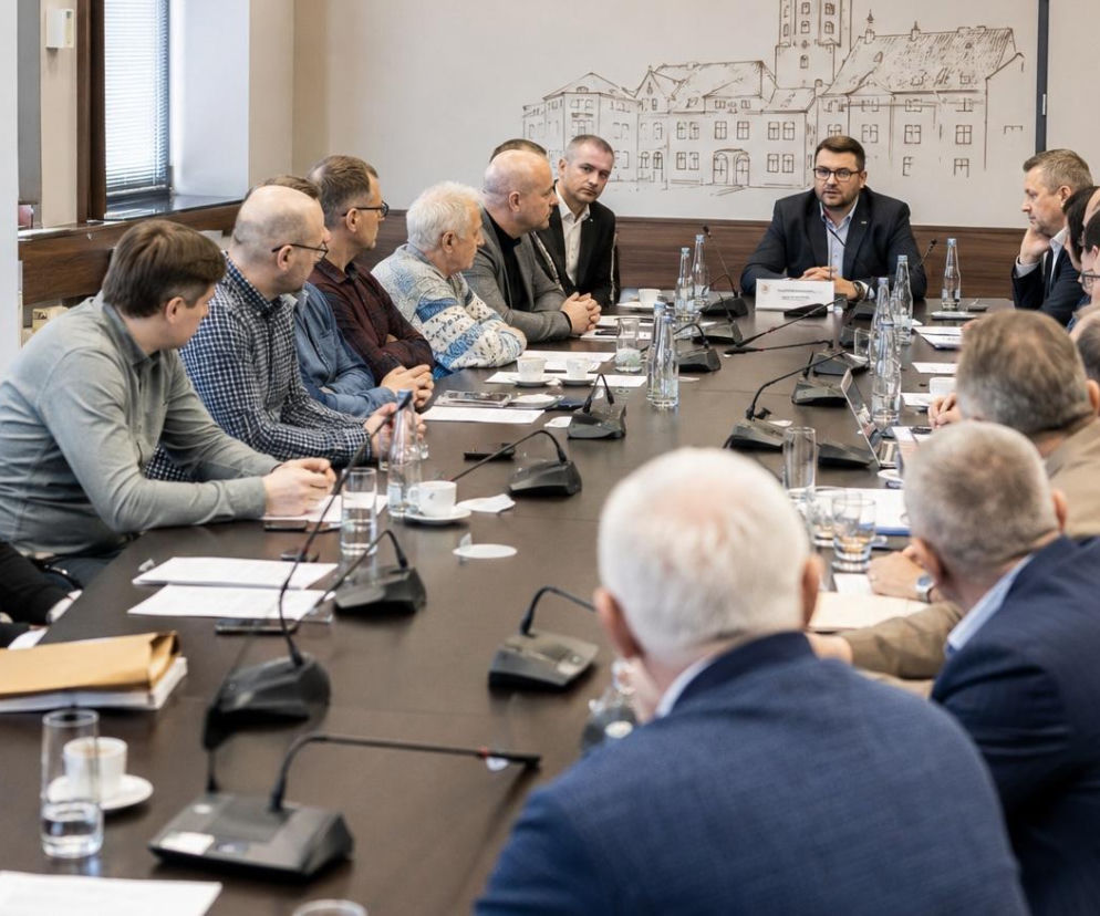 Grupa mężczyzn w różnym wieku, w tym przewodniczący Rady Miejskiej Paweł Szewczyk, siedząca przy długim stole podczas spotkania, omawiająca inicjatywę powołania rady mężczyzn, o której przeczytasz więcej na naszym portalu.
