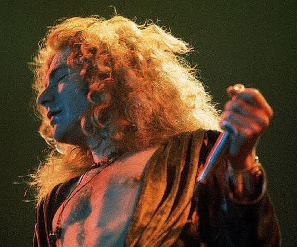 Młody Robert Plant z burzą blond włosów śpiewa do mikrofonu. O historii wokalisty Led Zeppelin przeczytasz na EskaRock.