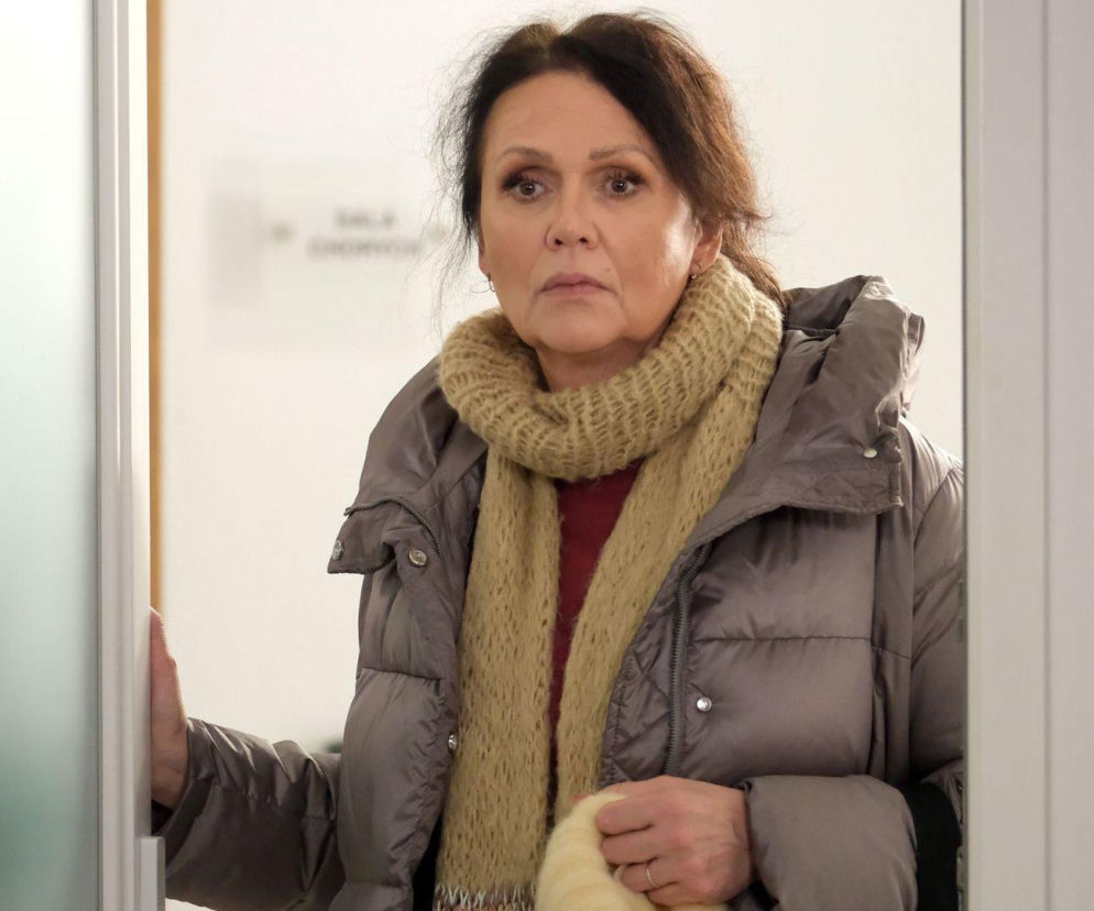 Małgorzata Pieńkowska jako Marysia Rogowska w „M jak miłość”, w szarym płaszczu puchowym i beżowym szaliku, wygląda na zmartwioną i zdeterminowaną. Scena z serialu o warunku, który Marysia stawia Pawłowi w związku z jego depresją, do przeczytania na Super Seriale.