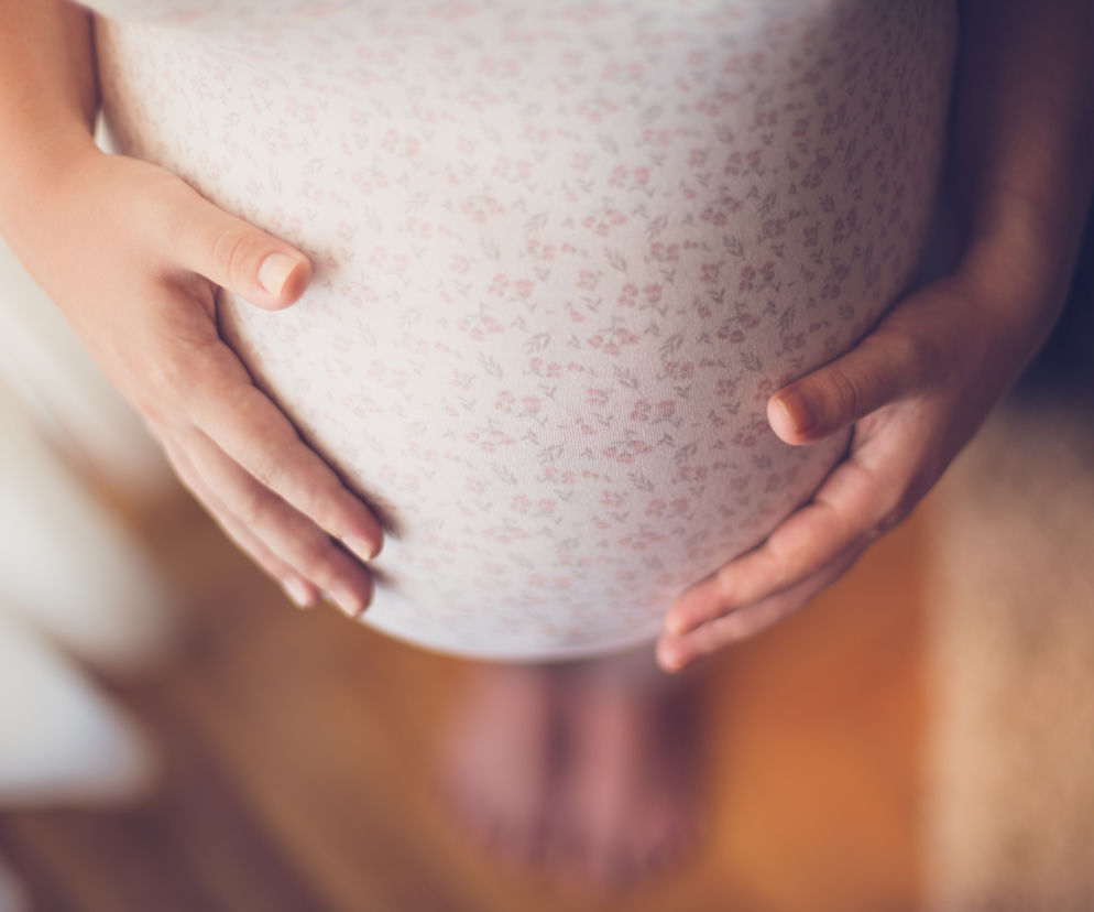 Zbliżenie na brzuch kobiety w ciąży. Czy szczepienia przeciw COVID-19 w ciąży są bezpieczne?