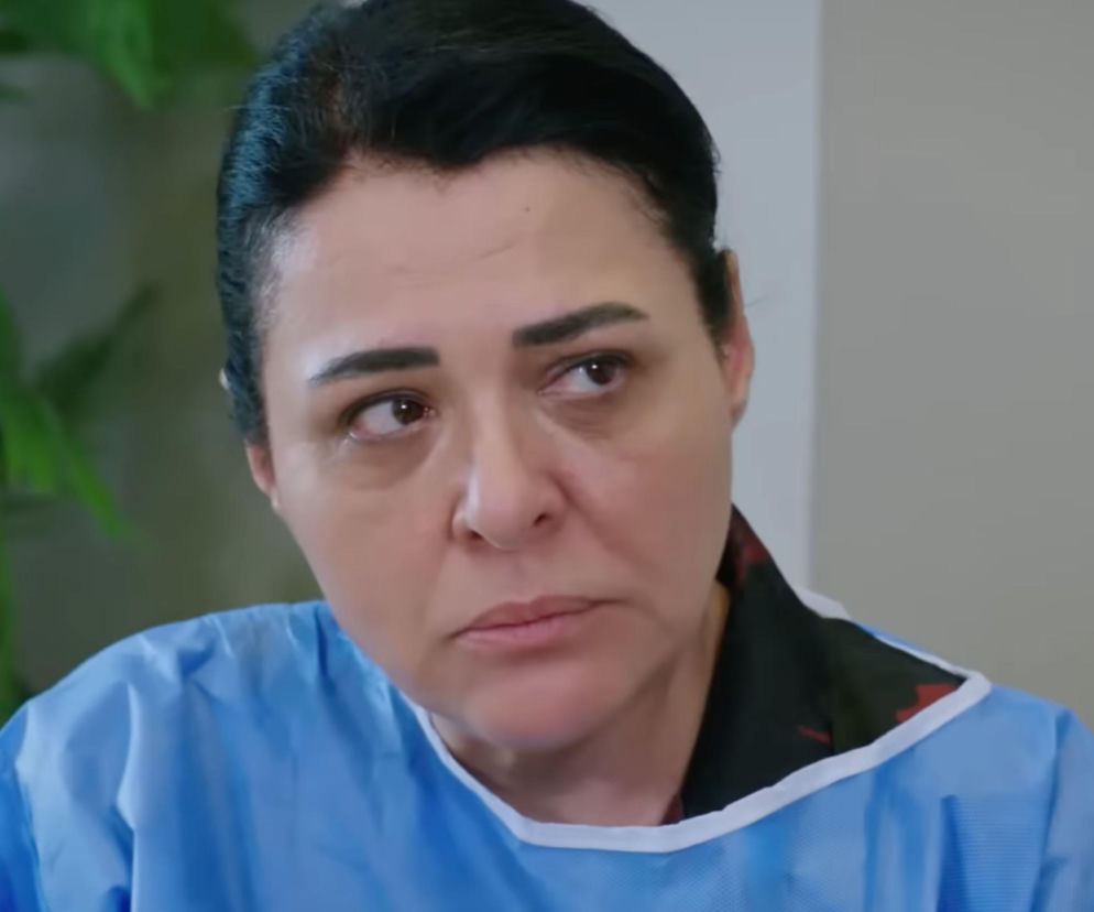 Betigül Ceylan jako Mukadder Develioglu w serialu Panna młoda, odcinek 106. Kobieta ubrana w niebieski medyczny strój, patrzy w prawo z poważnym wyrazem twarzy. Więcej informacji o serialu znajdziesz na Super Seriale.
