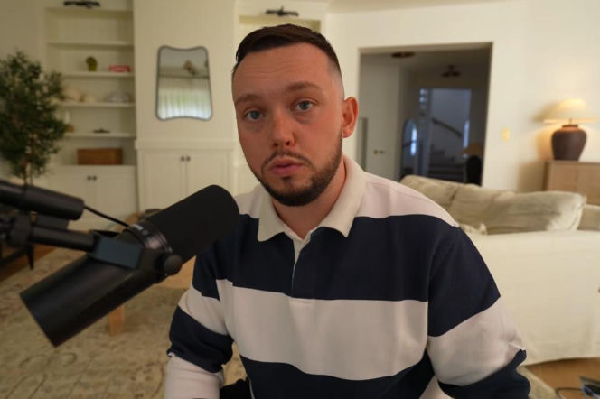 Youtuber Książulo w biało-granatowej koszulce polo siedzi przed mikrofonem. O krytyce jego pizzy przeczytasz na Eska.
