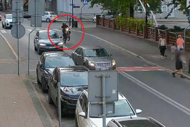 Osoba jadąca motorowerem na przednim kole wzdłuż samochodów w Kościanie. O rajdzie 16-latka przeczytasz w Eska Poznań.