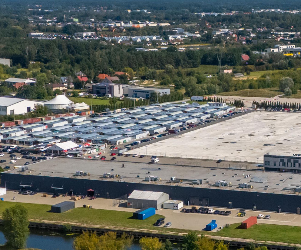 Widok z góry na tymczasowe miasteczko kontenerowe i pusty plac po spalonych halach. O odbudowie Marywilskiej 44 przeczytasz na Architektura.