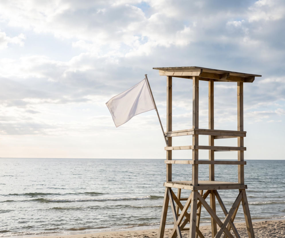 Drewniana wieża ratownika z białą flagą na plaży w Rewalu. O warunkach nad Bałtykiem przeczytasz na SE Szczecin.