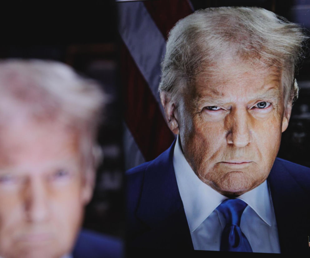 Były prezydent Donald Trump z poważną miną, w tle rozmazany jego wizerunek. Polityk nosi granatowy garnitur i krawat. Temat decyzji jego administracji odnośnie AI Mythos na portalu Super Biznes.