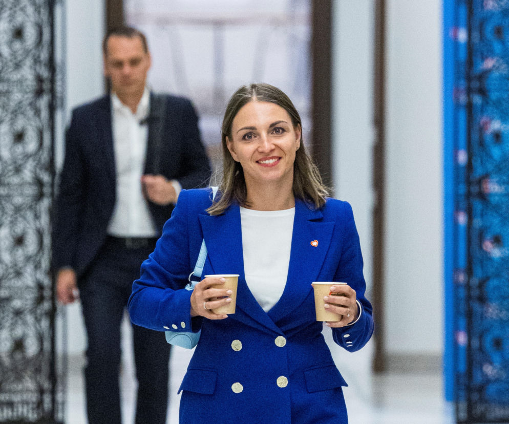 Uśmiechnięta posłanka Kinga Gajewska w chabrowej marynarce trzyma dwa kubki kawy. O jej wpisie przeczytasz na SE Polityka.