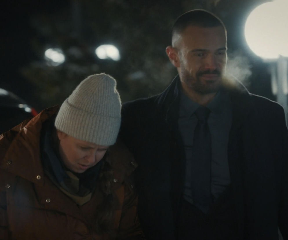 Mężczyzna, Mikołaj Krawczyk jako Sowiński, z opiekuńczym wyrazem twarzy idzie obok kobiety, Karoliny Dryzner jako Ewy w jasnej czapce, w scenie nocnej z serialu M jak miłość. Ich relacja i tajemnice są głównym tematem, o czym przeczytasz więcej na Super Seriale.