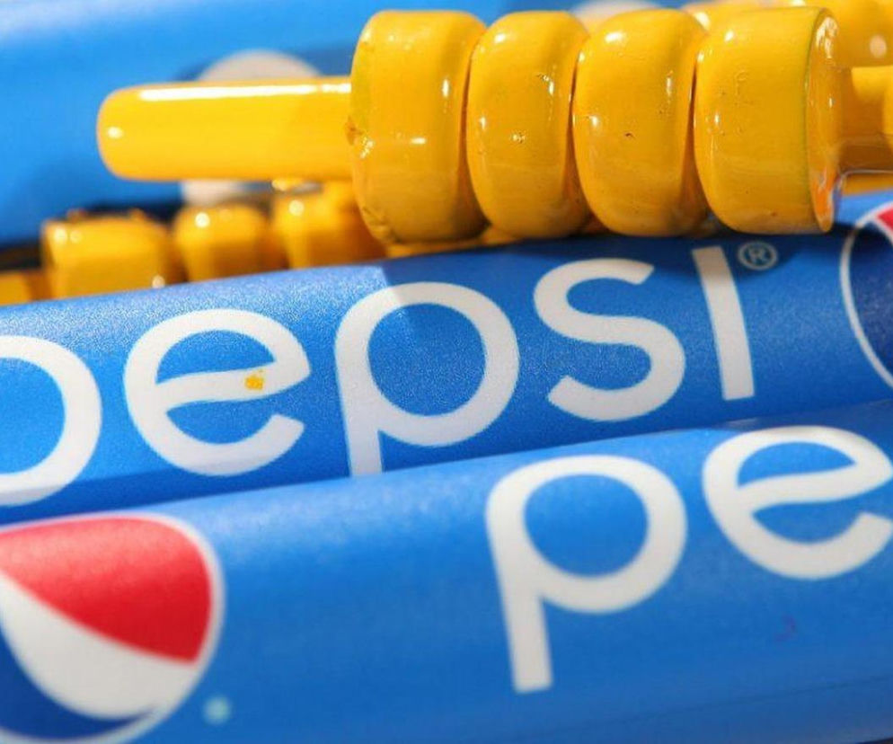 Niebieskie puszki napoju Pepsi z widocznym logo i częścią nazwy, na nich żółte, cylindryczne elementy. Zdjęcie ilustruje nietypową kampanię marketingową Pepsi z kebabem, o której przeczytasz na Super Biznes.