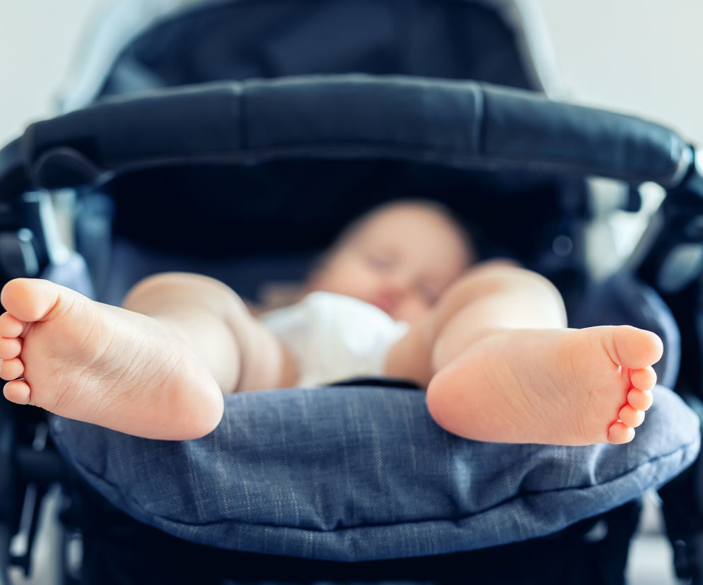 Nogi dziecka leżącego w wózku spacerowym. O powodach niechęci malucha do jazdy w wózku przeczytasz na SE.