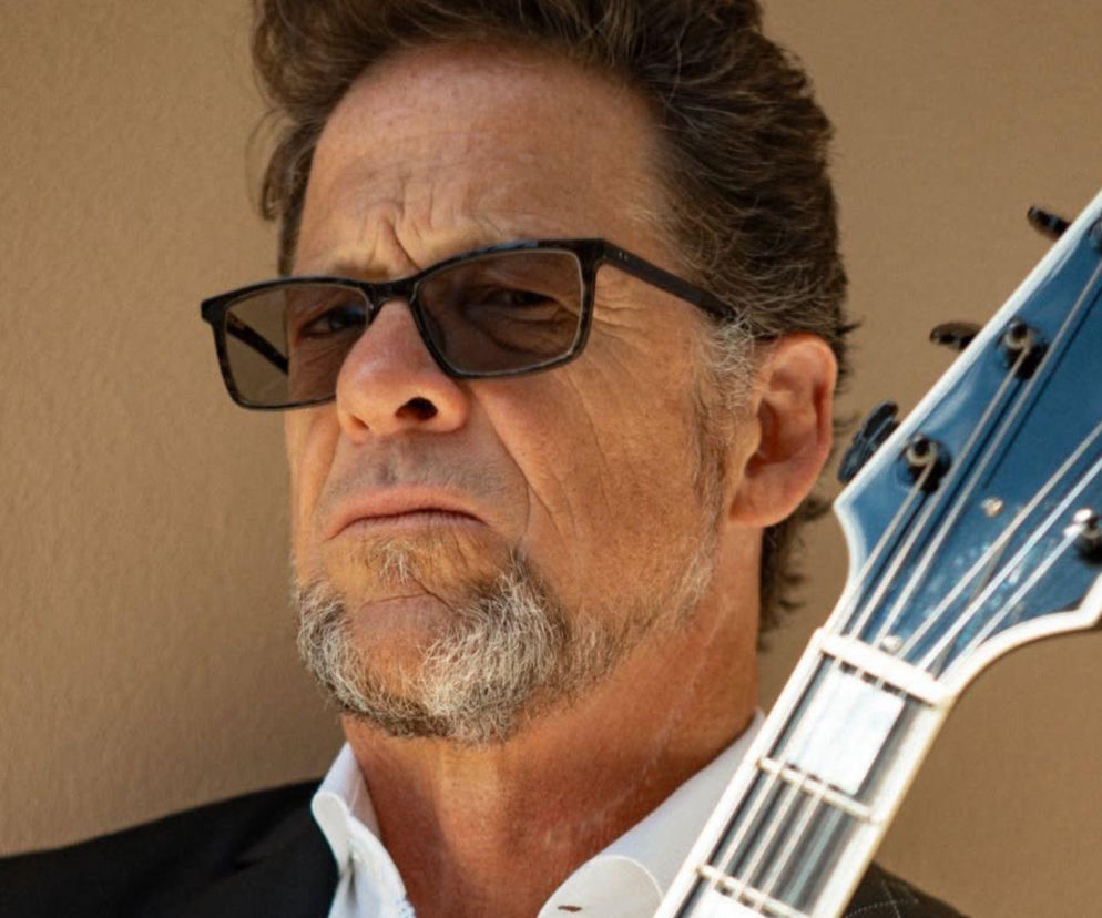 Jason Newsted w okularach stoi obok gryfu gitary. O walce muzyka z depresją przeczytasz na EskaRock.