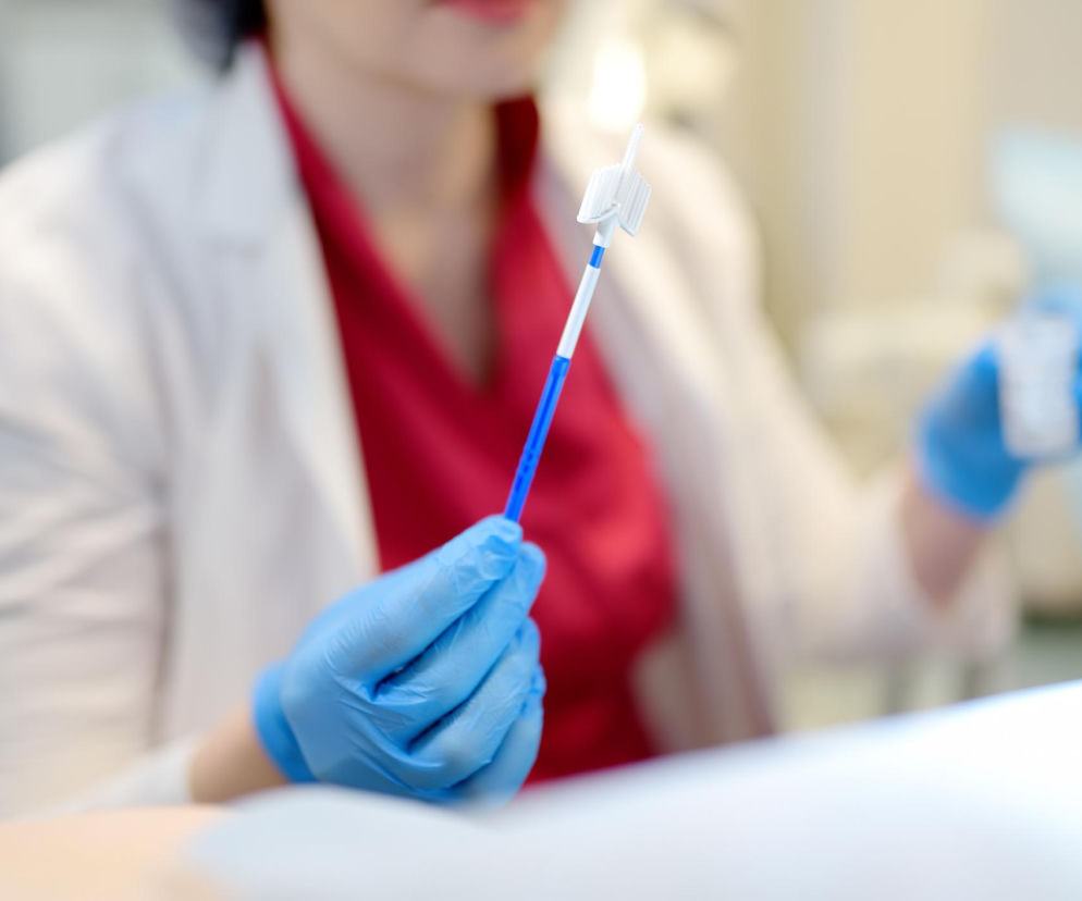 Lekarka w rękawiczkach trzyma szczoteczkę do cytologii. O zasadach przygotowania do badania przeczytasz na Poradnik Zdrowie.