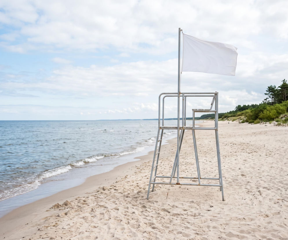 Biała flaga na wieży ratowniczej na pustej plaży w Grzybowie. O warunkach nad morzem przeczytasz na SE Szczecin.