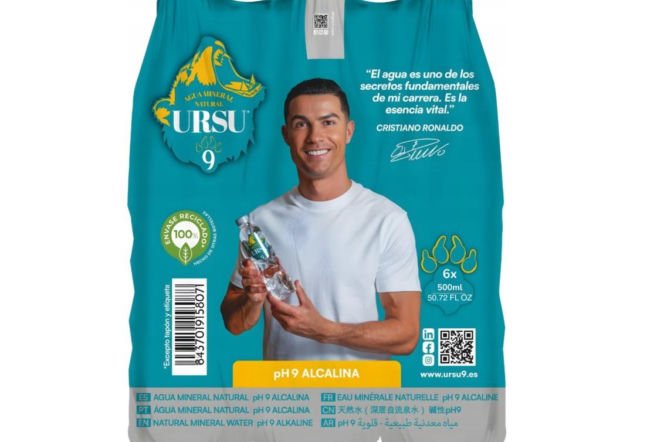 Cristiano Ronaldo z uśmiechem prezentuje butelkę wody alkalicznej URSU9 na opakowaniu reklamowym w turkusowych barwach. Na naszym portalu dowiesz się o nowościach rynkowych i cenie tej premium wody mineralnej o pH 9.