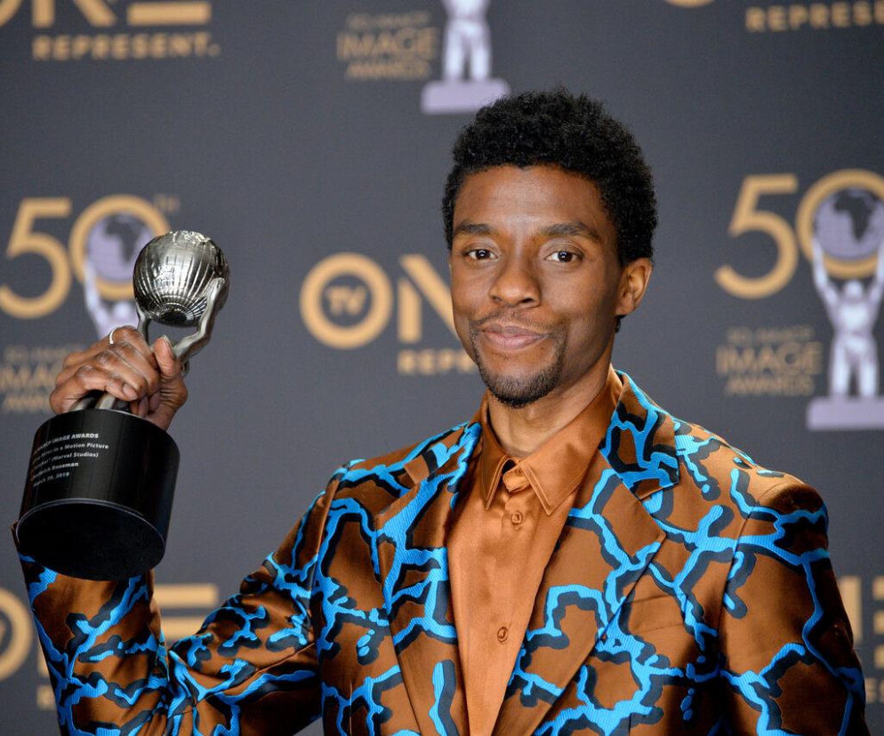Uśmiechnięty aktor Chadwick Boseman trzyma srebrną statuetkę. O jego następcy w nowym filmie przeczytasz na Eska.