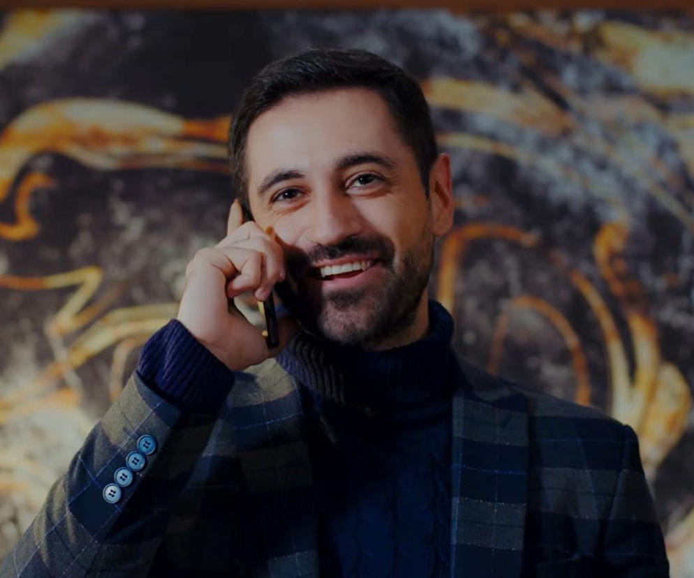 Uśmiechnięty Poyraz z serialu Dziedzictwo rozmawia przez telefon. O jego trudnych wyborach przeczytasz na Eska.