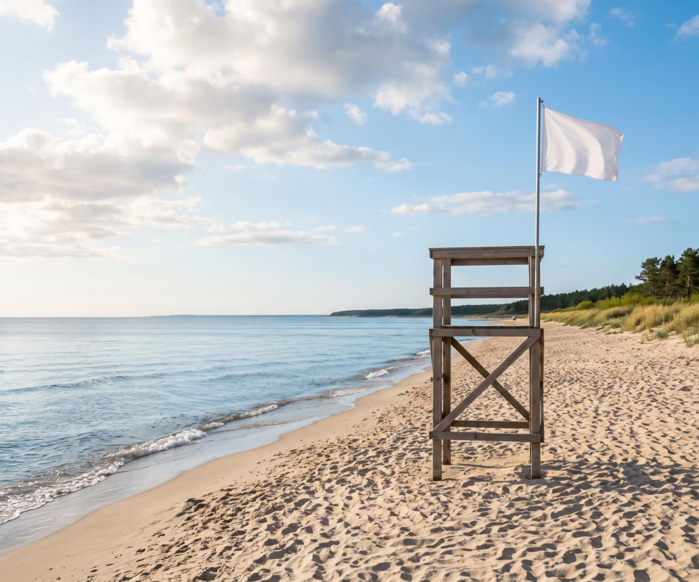 Biała flaga na wieży ratowniczej przy pustej plaży w Krynicy Morskiej. O bezpiecznej kąpieli czytaj na Eska Trójmiasto.