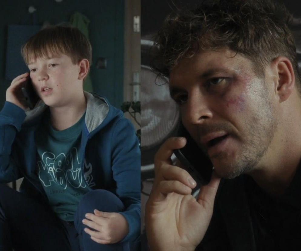 Szymek i Marcin Chodakowski rozmawiają przez telefon, Szymek w bluzie z kapturem, Marcin z widocznym podbitym okiem, wyglądającym na zmęczonego i zamyślonego. Emocjonalna scena z serialu M jak miłość, gdzie Szymek prosi ojca o zmianę zachowania. Więcej o ich losach na Super Seriale.